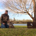 A hunter kneels by his big buck kill