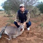 Hunter kneels by his whitetail buck