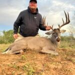 Hunter kneeling behind his good-looking whitetail deer buck kill