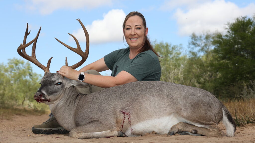 Woman poses with harvested whitetail buck