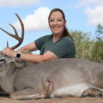 Woman poses with harvested whitetail buck